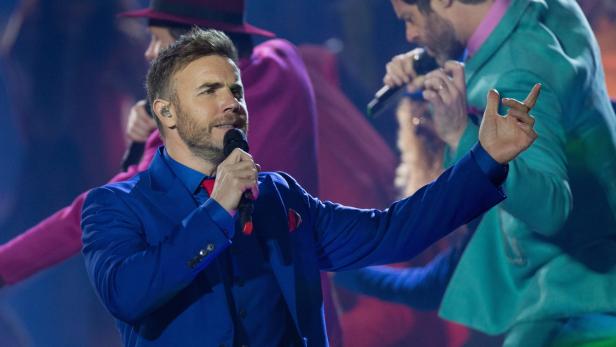 Gary Barlow singt in einem blauen Anzug auf der Bühne.