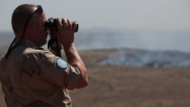 epa03734817 A UN peacekeeper watches with binoculars the Quneitra crossing (pictured in the backround), the only crossing between the Israel and Syria, in the Golan Heights, 07 June 2013. Clashes erupted on 07 June between Syrian government troops and rebels at a border crossing near the Israeli-occupied Golan Heights, activists said, a day after Damascus said it had regained control of the outpost. The pro-opposition Syrian Observatory for Human Rights, a Britain-based group monitoring the situation inside Syria, said fighting was raging in the town of Quneitra on the Syrian side of the Golan Heights. EPA/ATEF SAFADI