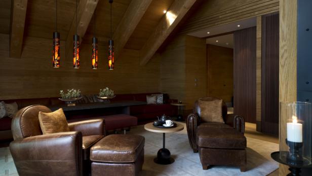 Bequeme Ledersofas, dicke Teppiche, kuschelige Fellpölster, edle Couchtische, todschicke Stehlampen und viele exklusive Wohnaccessoires: Der Raum ist mehr als gemütlich. Dabei ist er das, was in anderen Hotels "Skistall" heißt.