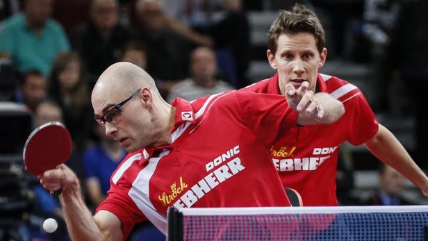 Zwei Tischtennisspieler in roten Trikots während eines Spiels.