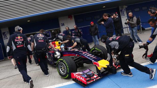 Ein Formel-1-Rennwagen wird von einem Team in der Boxengasse geschoben.