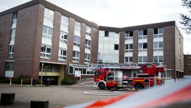 Ein rotes Feuerwehrfahrzeug der Feuerwehr Erkrath steht vor einem Backsteingebäude.
