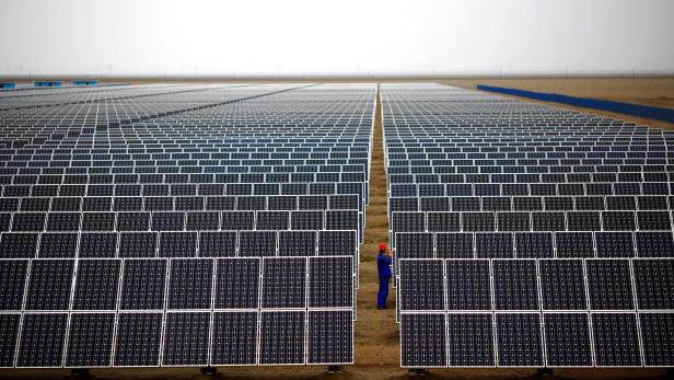 FILE PHOTO: A worker inspects solar panels at a solar farm in Dunhuang