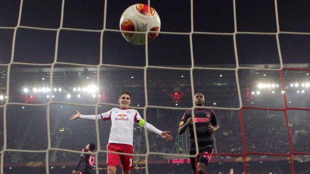 Ein Fußballspieler jubelt vor dem Tor, während ein Ball in der Luft ist.