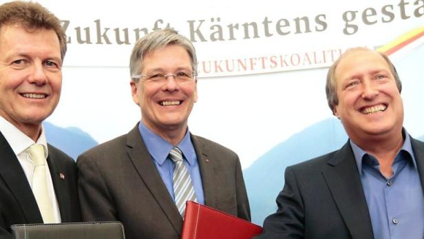 Drei lächelnde Männer in Anzügen stehen vor einem Banner der „Zukunftskoalition“.