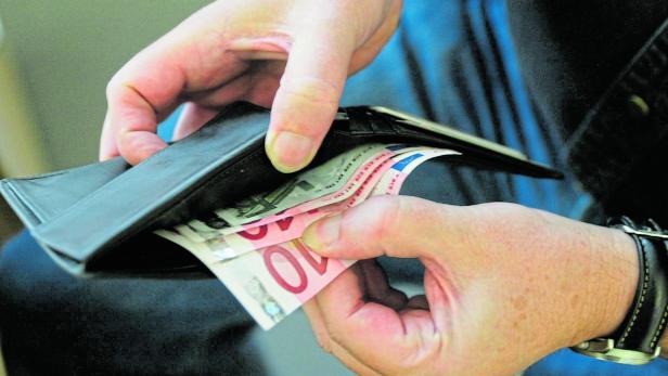 Eine Person zählt Geldscheine in einem schwarzen Portemonnaie.