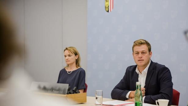 Ein Mann und eine Frau sitzen an einem Tisch bei einer Pressekonferenz.