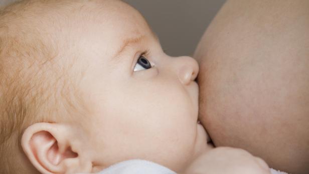 Ein Baby wird gestillt und blickt nach oben.