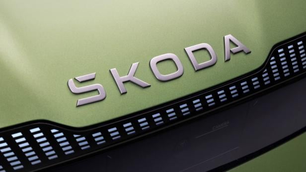 Das Skoda-Logo auf der Motorhaube eines grünen Autos.