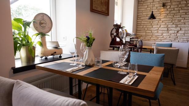 Ein gedeckter Tisch in einem Restaurant mit Dekorationen wie einer alten Waage und einer Aufschnittmaschine.