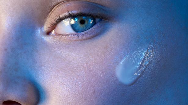 Nahaufnahme eines Frauengesichts mit einem Tropfen Creme auf der Wange.