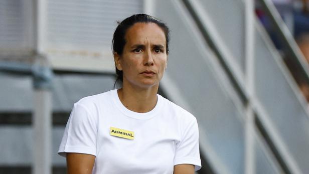 Eine Frau mit einem weißen T-Shirt mit dem Aufdruck „Admiral“ gestikuliert.