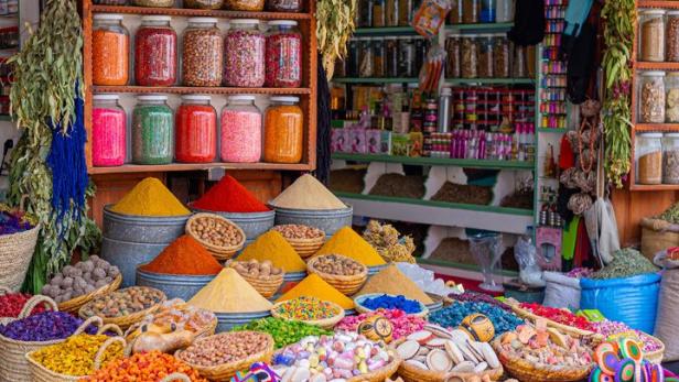 Ein Marktstand bietet eine Vielzahl von Gewürzen, Kräutern und Süßigkeiten in Körben und Gläsern an.