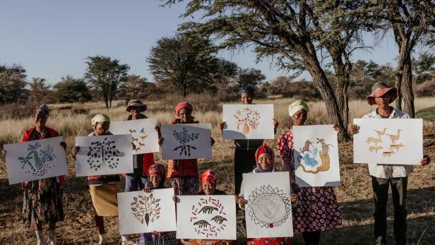 Eine Gruppe afrikanischer Frauen präsentiert ihre Zeichnungen in der Natur.
