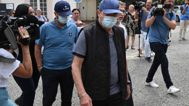 Männer mit Masken werden von Kameraleuten begleitet.