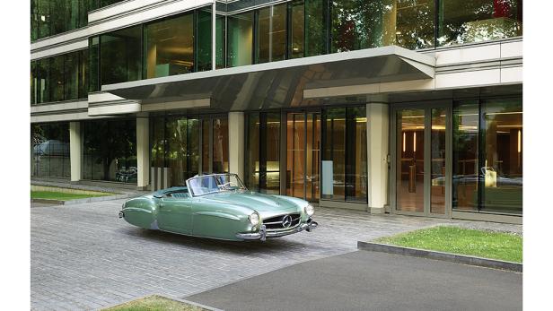 Ein mintgrüner Mercedes-Benz 190 SL Roadster vor einem modernen Gebäude.