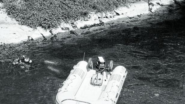 Ein Taucher im Wasser neben einem kleinen Schlauchboot mit Motor.