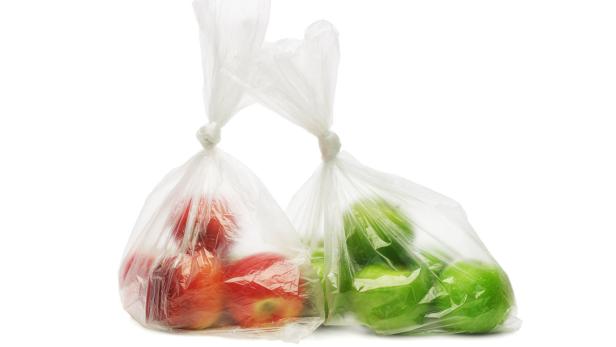 Zwei Plastiktüten, gefüllt mit roten und grünen Äpfeln.