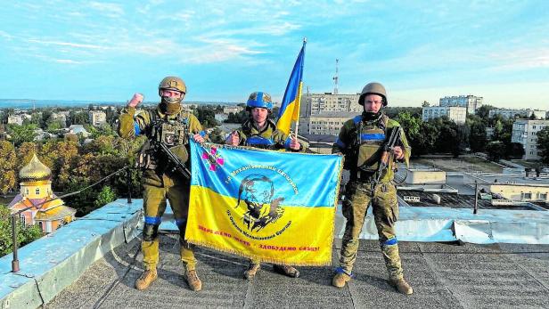 Ukrainische Soldaten halten eine Flagge auf einem Dach in Kupiansk.