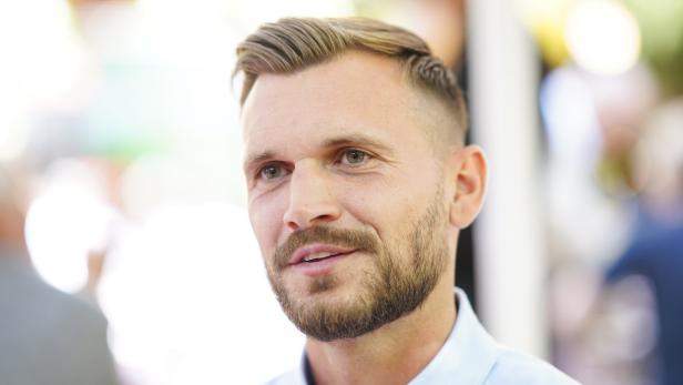 Porträt eines Mannes mit Bart und hellblauem Hemd.