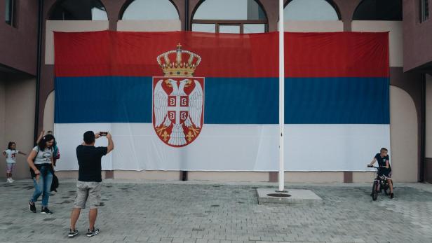 Kinder spielen vor einer serbischen Flagge im Norden von Mitrovica.