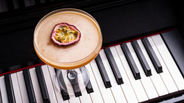 Ein Cocktail mit Passionsfruchtgarnitur steht auf einem Klavier.