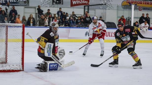 Ein Eishockeyspieler schießt auf das Tor, während der Torwart versucht, den Schuss abzuwehren.