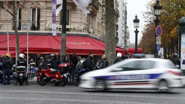 Vor dem Restaurant Fouquet's in Paris stehen Motorräder und ein Polizeiauto fährt vorbei.