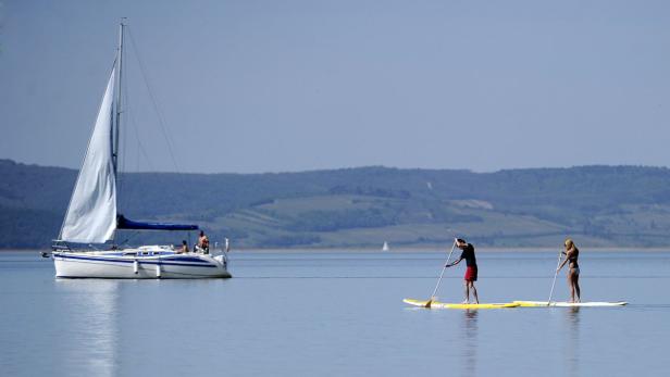 APA/HELMUT FOHRINGERAPA7695748-2 - 27042012 - PODERSDORF - ÖSTERREIC APZU APA-TEXT CI - THEMENBILD - Illustration zum Thema WETTER / HITZE / SOMMER. Im Bild: Ein Mann und eine Frau auf einem Surfbrett aufgenommen am Freitag, 27. April 2012, am Neusiedler