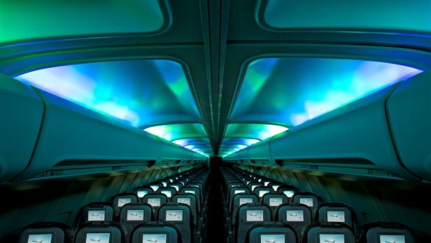 Innenansicht eines Flugzeugs mit blauer und grüner Beleuchtung.