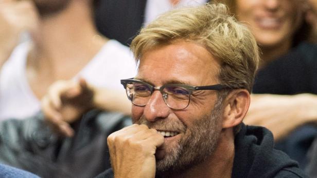 Jürgen Klopp mit Brille lächelt und hält die Hand vor den Mund.