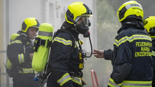Mehrere Feuerwehrleute mit Atemschutzgeräten im Einsatz.