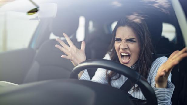 Eine wütende Frau gestikuliert im Auto während eines Staus.