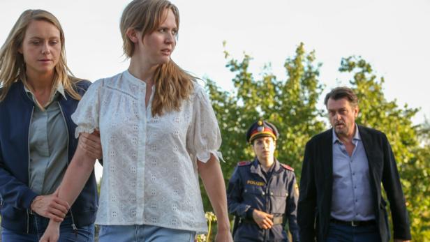 Zwei Frauen werden von einem Mann und einer Polizistin begleitet.