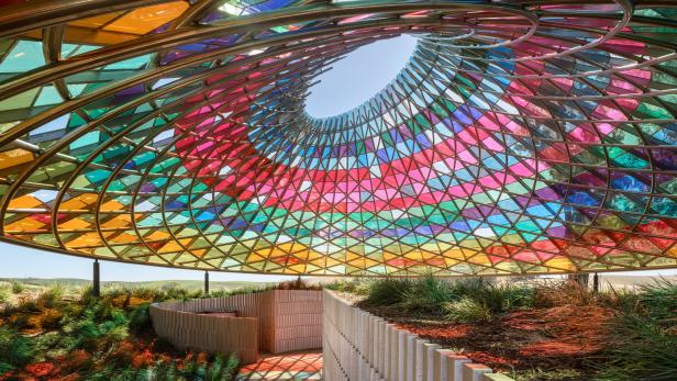 Ein farbenfroher Pavillon mit einem Dach aus Buntglas und einer spiralförmigen Öffnung zum Himmel.