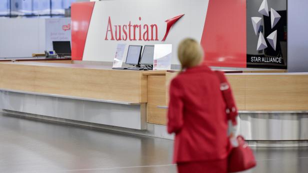 Eine Frau geht auf einen Check-in-Schalter der Austrian Airlines zu.