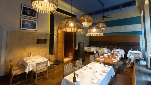 Ein elegantes Restaurant mit gedeckten Tischen und auffälligen Korbleuchten.