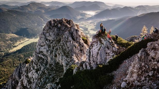 Wanderer genießen die Aussicht von einem felsigen Gipfel in den Wiener Alpen bei Puchberg.