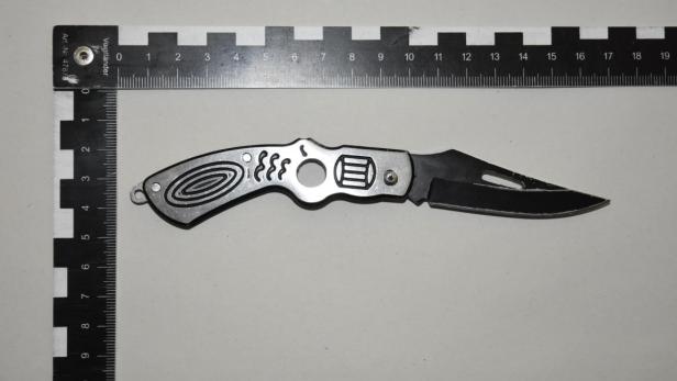 Ein Taschenmesser liegt auf einem Lineal.