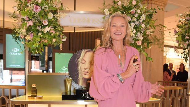 Kate Moss posiert vor einem Regal mit „Cosmoss“-Produkten.