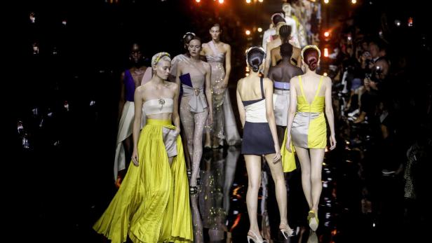 Models präsentieren farbenfrohe Designs auf einem Laufsteg.