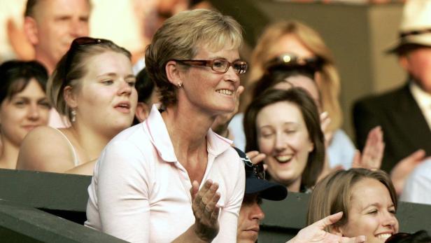 Eine Frau mit Brille klatscht inmitten einer jubelnden Zuschauermenge.