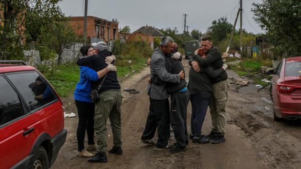 Neighbours embrace each others after they return from evacuation to liberated village in Kamianka