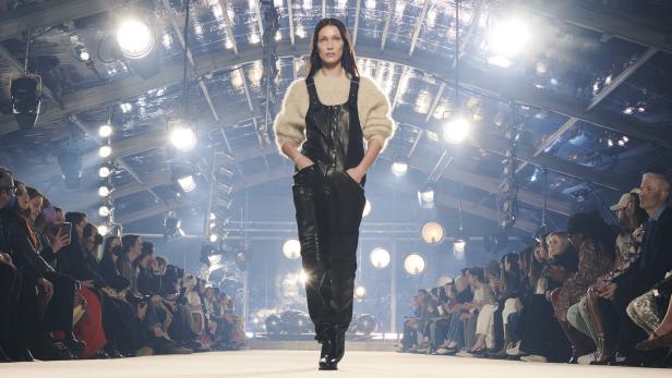 Bella Hadid läuft in einem schwarzen Lederoverall über einen Laufsteg.