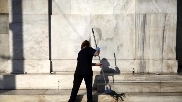 FILE PHOTO: A cleaning lady mops the steps at the main entrance of the Bank of Greece headquarters in Athens