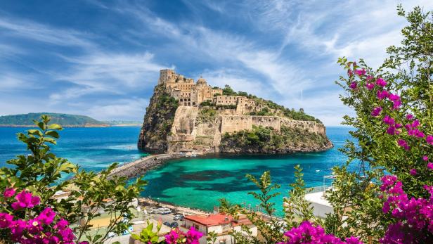 Das Castello Aragonese thront auf einer Felseninsel vor Ischia, verbunden durch einen Steg.