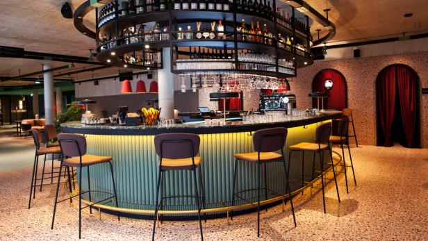 Eine Bar mit Hockern und einer großen Auswahl an Getränken in Regalen über der Theke.