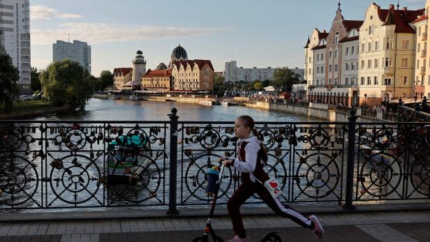 A girl rides a scooter on an embankment of the Pregolya River in Kaliningrad