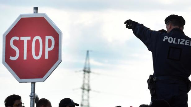 Ein Polizist steht neben einem Stoppschild und gibt Anweisungen.