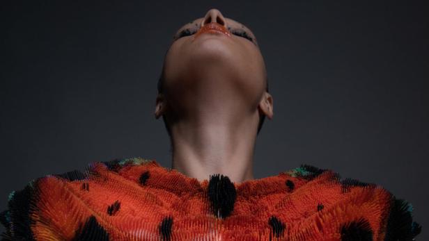 Eine Frau trägt ein Oberteil, das einem Schmetterling ähnelt.